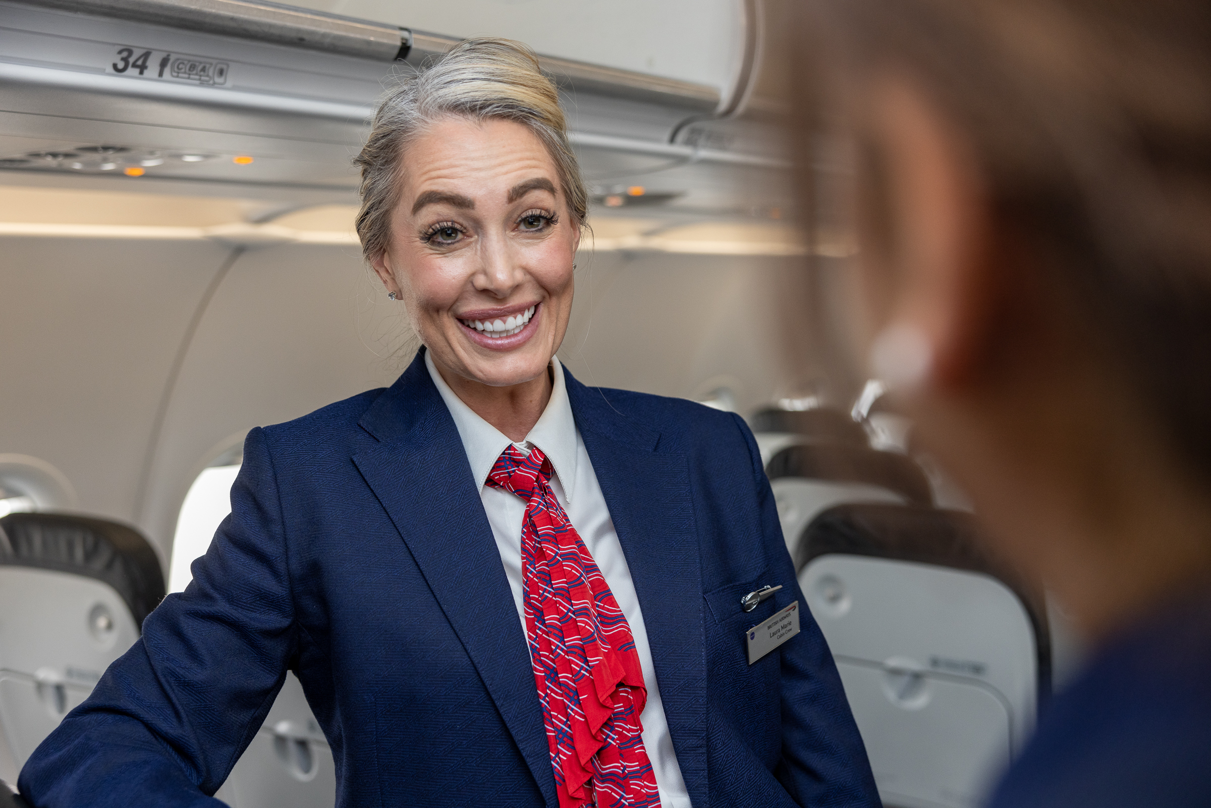 Member of British Airways cabin crew talking to person on board