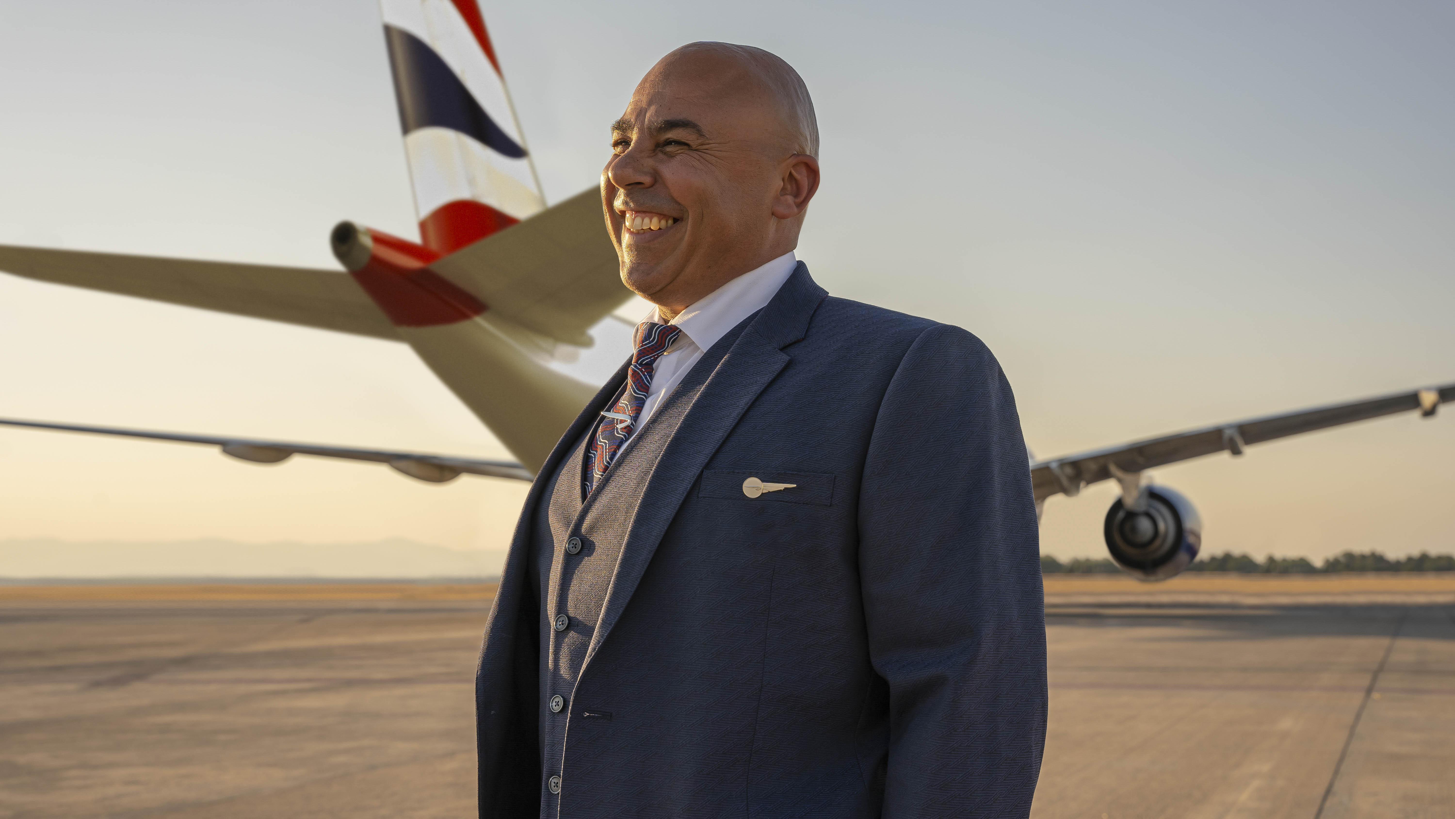 Member of British Airways cabin crew standing in front of plane